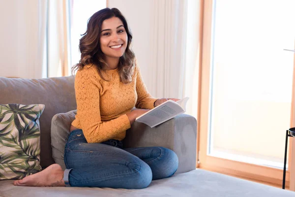 Frau liest Buch auf Sofa — Stockfoto