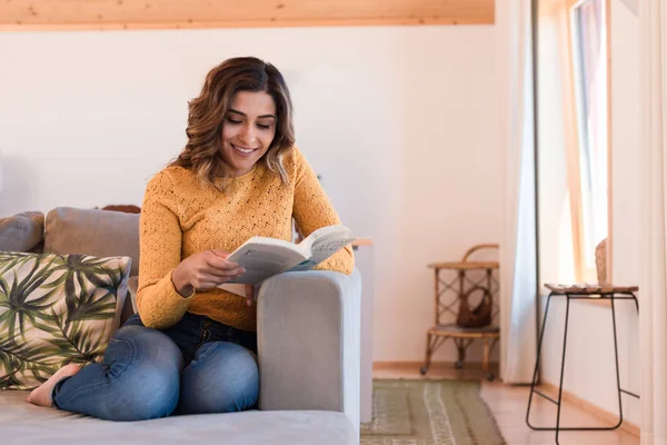 Frau liest Buch auf Sofa — Stockfoto