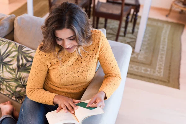 Nő olvasás könyvet kanapén — Stock Fotó