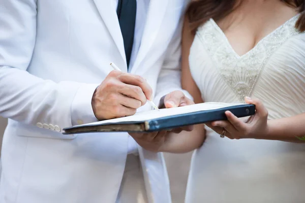 Noiva e noivo em terno branco assinando sua licença de casamento — Fotografia de Stock