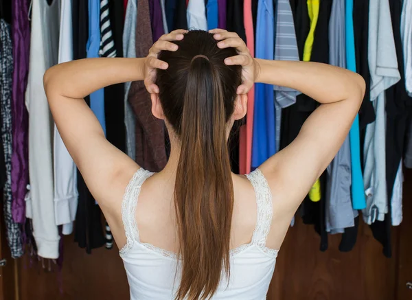 Frustrierte junge Frau kann sich nicht entscheiden, was sie aus ihrem Kleiderschrank anzieht — Stockfoto