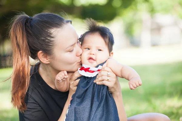 Jovem mãe beija seu bebê bonito na bochecha — Fotografia de Stock