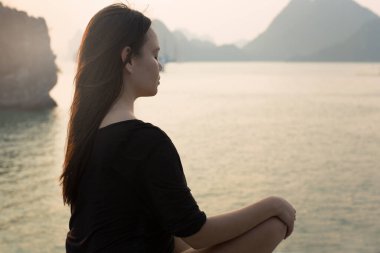 Huzurlu bir kadın okyanusun kenarında meditasyon yapıyor. Doğa rahatlaması.
