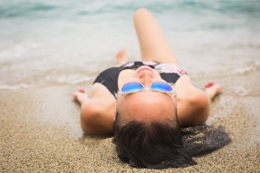 Deniz kıyısında uzanan seksi bir kadın. Gözleri kapalı okyanus suyu. Mutluluk ve yaz tatili..