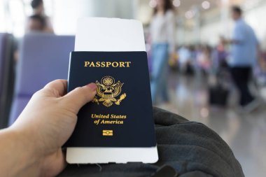 Havaalanı kapısında elinde pasaportu ve biletiyle bekleyen bir yolcu..