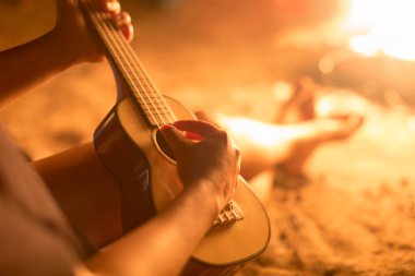 Dışarıda gitar çalan bir bayan müzisyen, ateşin yanında oturuyor. Rahatlama.
