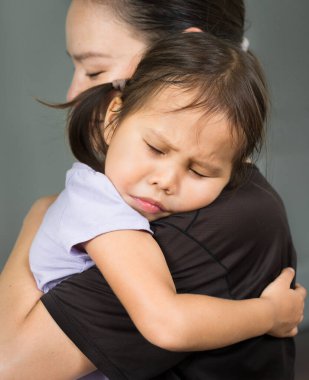 Genç çocuk güvende ve güvende hissetmek için annesini tutuyor. Aile sevgisi ve destek.