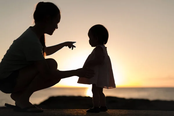 Sylwetka Rodzica Rozmawiającego Dzieckiem Zachodem Słońca Horyzoncie Wodnym — Zdjęcie stockowe