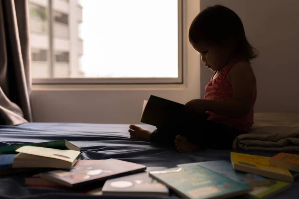 ベッドの上で本を読んでいるスマート若い子 — ストック写真