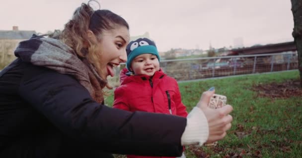 A irmã mais velha feliz com o irmão fotografa-se na floresta. Estão a tirar selfie no telemóvel. 4k — Vídeo de Stock