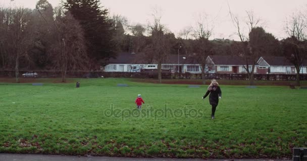 Ein glückliches Kind läuft seiner geliebten Mutter auf dem grünen Rasen im Park hinterher. 4k — Stockvideo