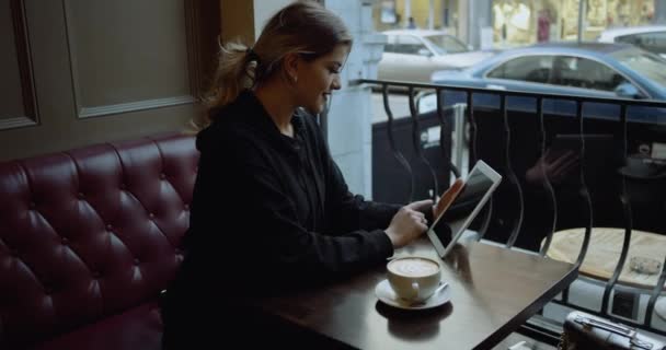 Mujer joven feliz con el ordenador tableta en la cafetería. 4k — Vídeos de Stock