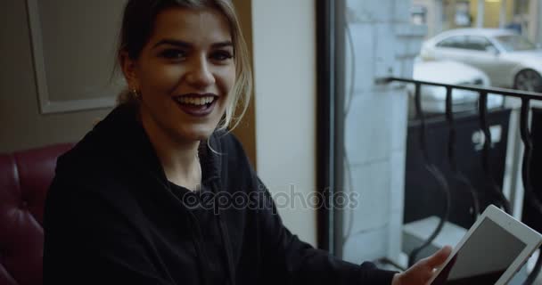 Портрет красивой, счастливой женщины с планшетным компьютером в кафе. 4k — стоковое видео