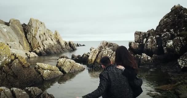 Pareja feliz enamorada lanzando piedras al mar. Movimiento lento . — Vídeos de Stock
