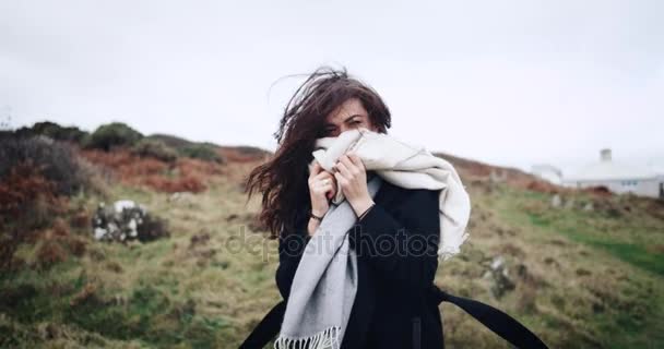 Une dame avec l'écharpe en caméra avant flirter, aller sur un terrain montagneux sur le bord de la mer. au ralenti. 4k — Video