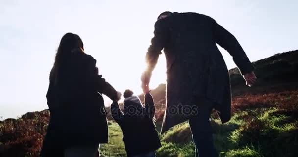 Счастливая семья Отец, мать и маленький мальчик бегают по полю на фоне заката. 4k . — стоковое видео
