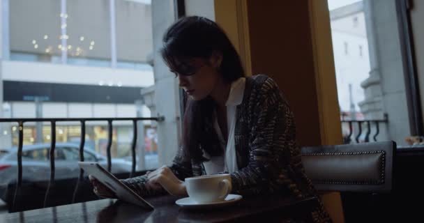 Женщина с планшетным компьютером пьет кофе в кафе. 4k — стоковое видео