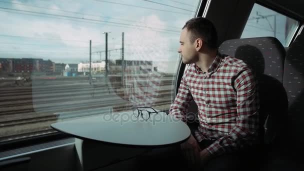 Jongen kijkt uit trein raam buiten, in de avond, reizen. 4 k. dimmen jongen in venster. Uitzicht op de stad. — Stockvideo
