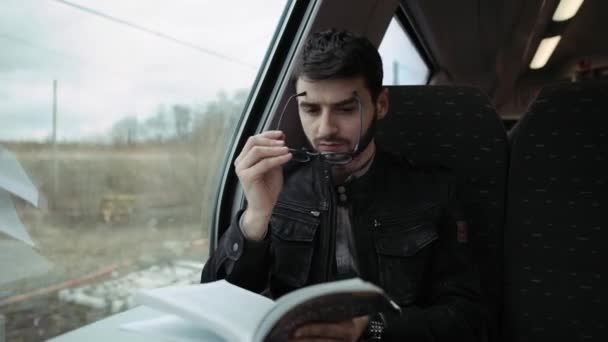 Junge reitet Zug und liest Buch. Junge mit Brille. 4k — Stockvideo