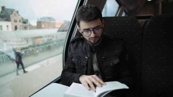 Un niño caminando en un tren, leyendo un libro. Un chico con gafas. 4k — Vídeo de stock
