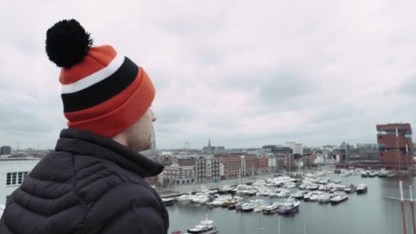 Man in special coloring hat, standing on barrier on roof, , looking into distance. 4k — Stock Video