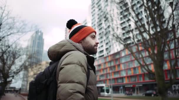 Un turista masculino con un sombrero colorido, mirando hacia otro lado. Ciudad desarrollada. 4k — Vídeo de stock