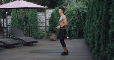Genç güzel atlet ile egzersiz yaparak atlar ve eller ev bahçe salıncak. Video 4 k yavaş hareket.