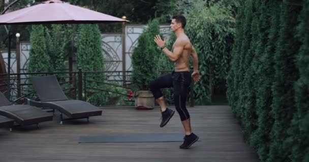 4K Atleta caldo che fa esercizio in palestra. Maschio facendo esercizio di plyometria in giardino di casa. Girato su Red Epic rallentatore — Video Stock