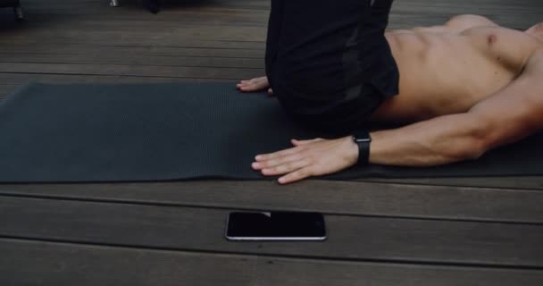 Un hombre joven, atleta tiene un buen cuerpo haciendo un crujido de bicicleta en aoutdor. 4k — Vídeo de stock