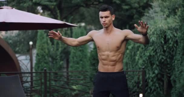 Atractivo atleta masculino muscular haciendo ejercicio con saltos y columpios manos en el jardín en casa — Vídeo de stock