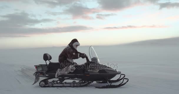 Turista en abrigo de reno ártico tradicional conduciendo moto de nieve en el lago congelado. Expedición Yamal 2016. Disparo en rojo épica lenta motion.HD — Vídeos de Stock