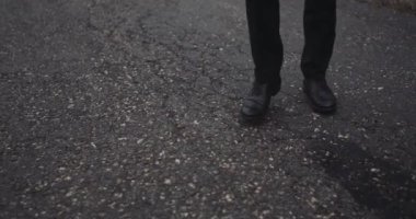 Siyah ayakkabı yavaş hareket görünümü, aşağı yolda yürürken bir adam. 4k