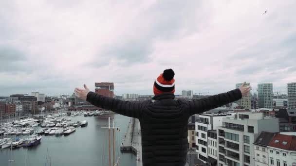 Mladý pohledný zvedni ruce na střeše mrakodrapu v pozadí průmyslových panoráma. — Stock video