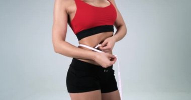 Atletik kadın bedeni nerede o karın beyaz arka plan için bant ile ölçüyor. 4k