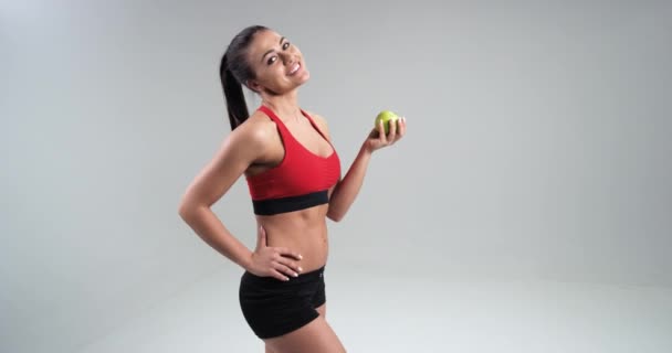 Veautiful atletisk flicka äter grönt äpple, begreppet idrott och en hälsosam kost. 4k — Stockvideo