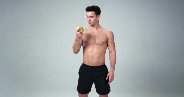 Egy férfi fitness modell azt mondja, igen, alma, boldog és egészséges életet. Fehér háttér. 4k — Stock videók