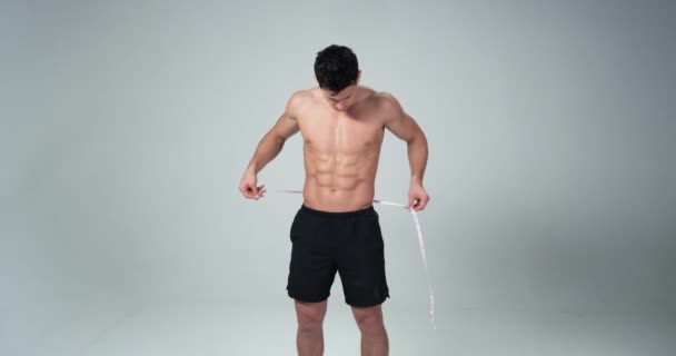 Young muscular man measuring his waist on white background. 4k — Stock Video