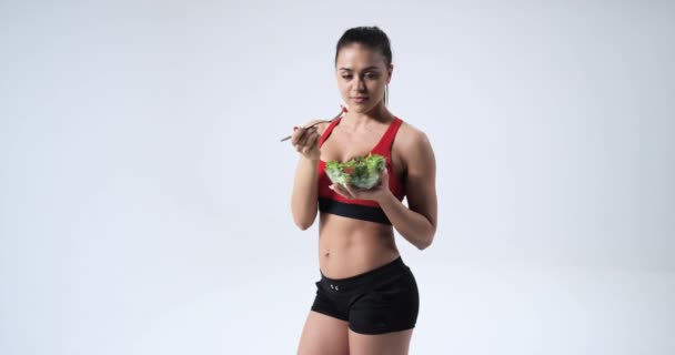 Atlético Fitness menina comendo salada de legumes e sorrindo, conceito de estilo de vida saudável, em fundo branco.4k — Vídeo de Stock