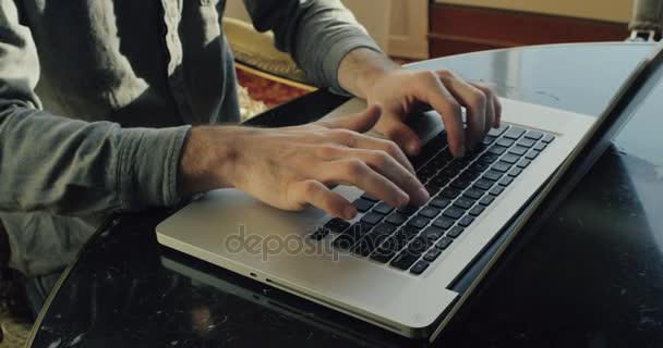 Mans hands are typing on the keyboard of the laptop at the office. New model of the laptop is on the table. 4k — Stock Video