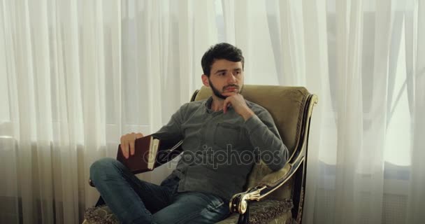 肘掛け椅子に座っていると、高級ホテルのロビーで休んでいる間彼の考えに笑顔の男。4 k. は立ち上がって行く. — ストック動画