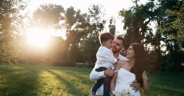 Mom, Dad and kid laughing and hugging, enjoying nature outside. Slow motion. The boy staggered. 4k. — Stock Video