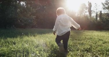 Küçük çocuk dışında çalışan. Ultra ağır çekim dış ev bahçesinde çalışan çocuk. Çocuk günbatımı için çalışır. 4k