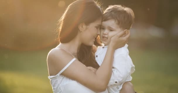 Mamma felice che abbraccia suo figlio al parco, al rallentatore. vestiti bianchi. Epica rossa — Video Stock