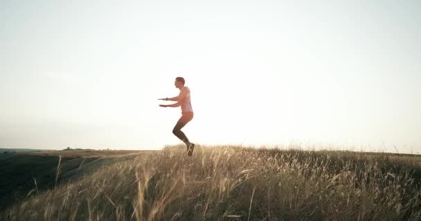 Člověk dělá burpees cvičení fitness cvičení venku. Zpomalený pohyb. Skok ve vzduchu rukama dotýká kolena. — Stock video
