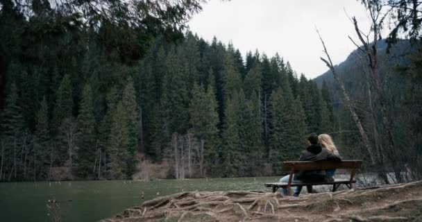 Young couple seating on the wooden bench. Looked at the lake — Stock Video