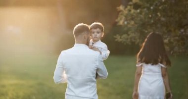 Üç alanın karşısındaki yürüyen genç aile. Karısı onun ikinci çocuğuna hamile olduğunu.