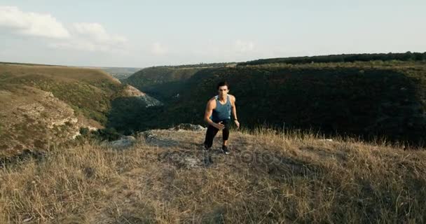 Hombre sano, joven, guapo, atractivo, blanco que se calienta para una carrera matutina en un pico de montaña. Épica roja — Vídeo de stock