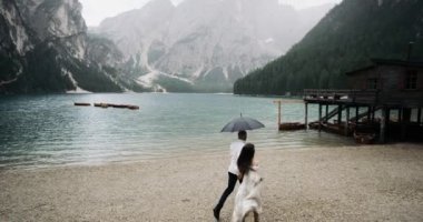 Harika manzara büyük göl ve dağların yağmur günde çift ahşap eve şemsiyesi altında çalışan ile. Ağır çekim. 4 k. kırmızı Epic. Lago de Braies
