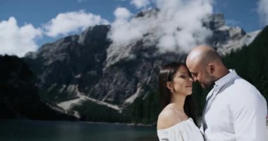 Yakın çekim genç çift aşık tutkuyla birbirleri ile ortasında harika manzara dağlar kara sevdanın içinde dolu arka planda oynuyorlar. 4k