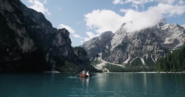 Simplemente increíble paisaje con grandes montañas con gran lago y una pareja romántica en el medio del lago con un barco de madera. 4k — Vídeo de stock
